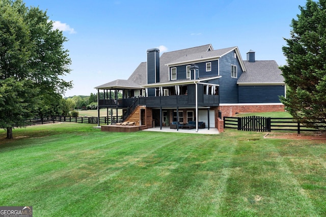 rear view of property featuring a wooden deck, a patio, a sunroom, and a lawn