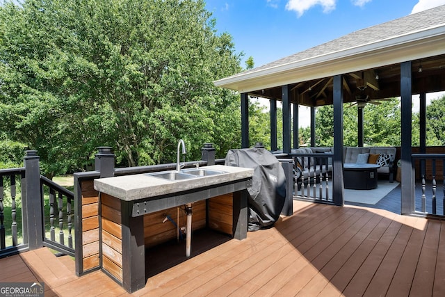 wooden terrace featuring ceiling fan, an outdoor wet bar, and grilling area