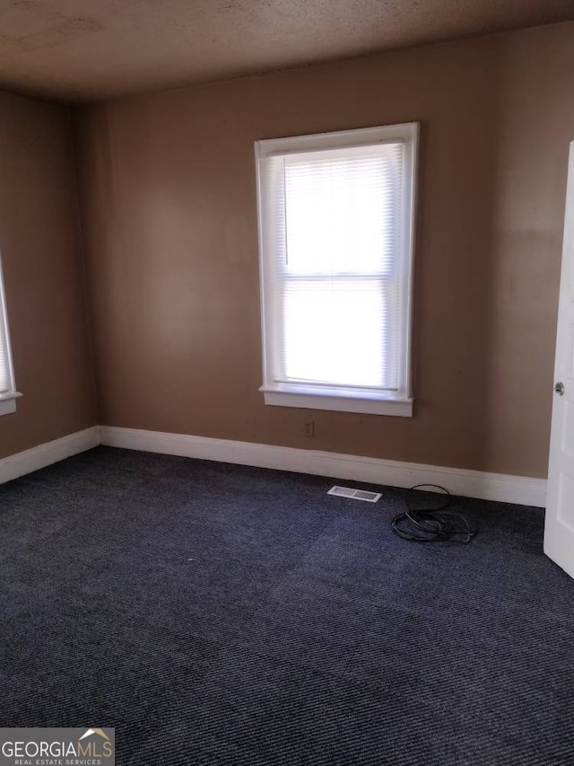 carpeted empty room with a textured ceiling