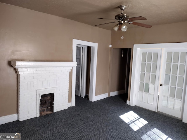 unfurnished living room with a textured ceiling, ceiling fan, dark carpet, and a fireplace