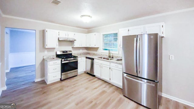 kitchen with appliances with stainless steel finishes, light wood-type flooring, ornamental molding, sink, and white cabinetry