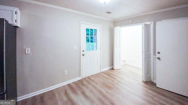 foyer entrance with ornamental molding and light hardwood / wood-style floors