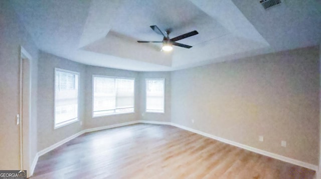 spare room featuring a raised ceiling, ceiling fan, and wood-type flooring