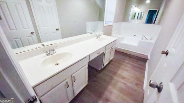 bathroom with vanity, a tub to relax in, and hardwood / wood-style flooring