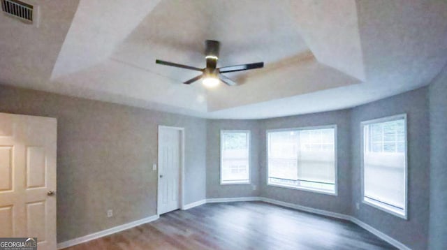 spare room featuring ceiling fan, hardwood / wood-style flooring, and a tray ceiling