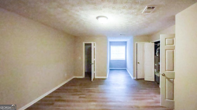 corridor with a textured ceiling and hardwood / wood-style floors