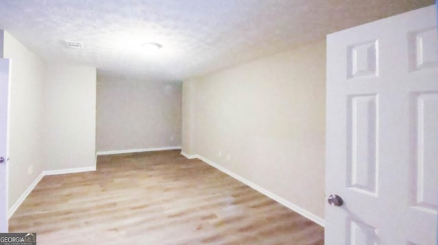 empty room featuring a textured ceiling and light hardwood / wood-style flooring