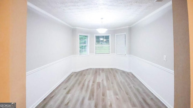 empty room with light hardwood / wood-style floors, ornamental molding, and a textured ceiling