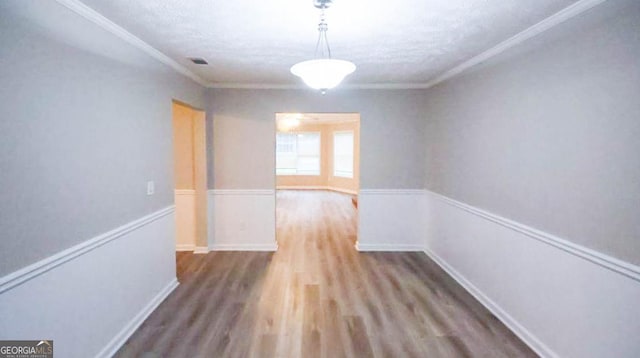 unfurnished dining area with a textured ceiling, ornamental molding, and wood-type flooring