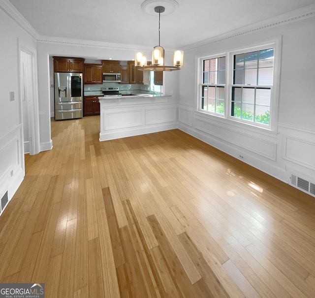 kitchen with stainless steel appliances, light hardwood / wood-style flooring, a notable chandelier, kitchen peninsula, and decorative light fixtures