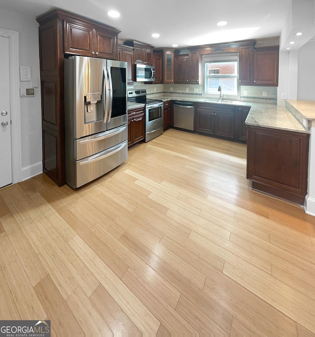 kitchen featuring decorative backsplash, sink, light stone counters, and stainless steel appliances