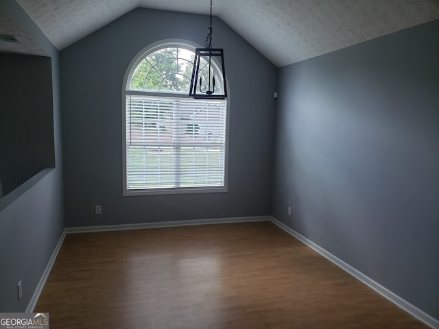 spare room featuring a textured ceiling, hardwood / wood-style flooring, and vaulted ceiling