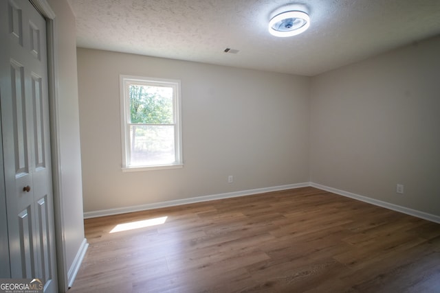 spare room with light wood-type flooring and a textured ceiling