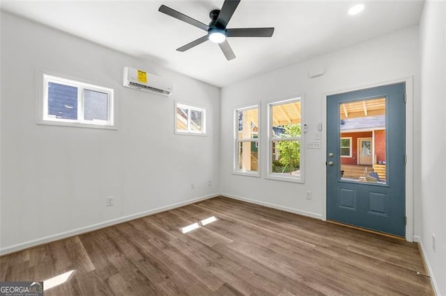 interior space with a wall mounted air conditioner, hardwood / wood-style flooring, and ceiling fan