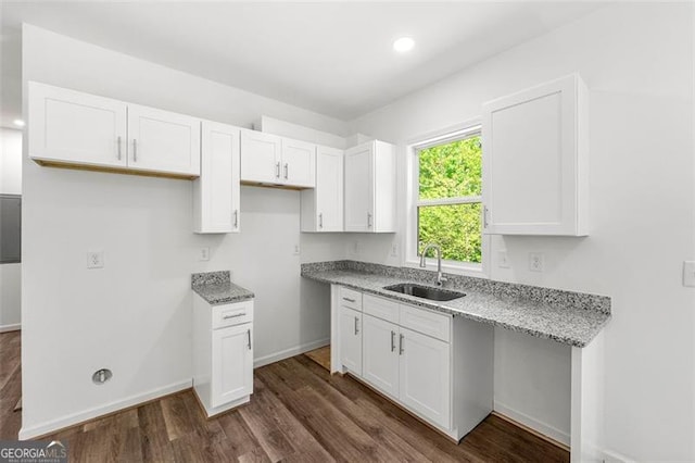 kitchen featuring light stone counters, sink, and white cabinets