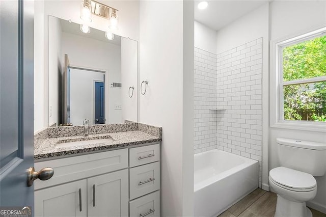 full bathroom featuring vanity, tiled shower / bath combo, wood-type flooring, and toilet