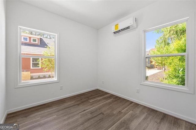 spare room with a wall mounted air conditioner and hardwood / wood-style floors