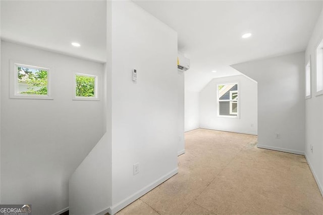 additional living space featuring lofted ceiling, plenty of natural light, and a wall unit AC