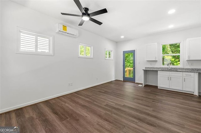 interior space with ceiling fan, dark hardwood / wood-style floors, sink, and an AC wall unit