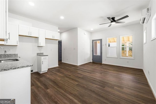 kitchen featuring dark wood-type flooring, sink, white cabinetry, a wall mounted air conditioner, and light stone countertops