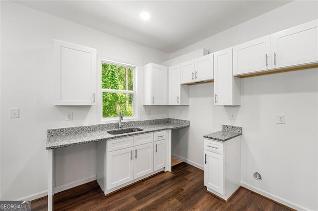 kitchen with white cabinetry, sink, light stone counters, and dark hardwood / wood-style flooring