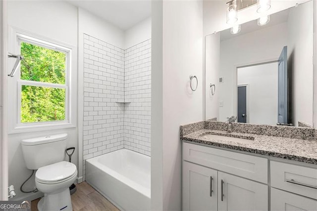 full bathroom with tiled shower / bath, vanity, toilet, and wood-type flooring