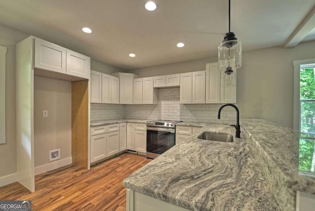 kitchen with stainless steel electric stove, tasteful backsplash, sink, and pendant lighting