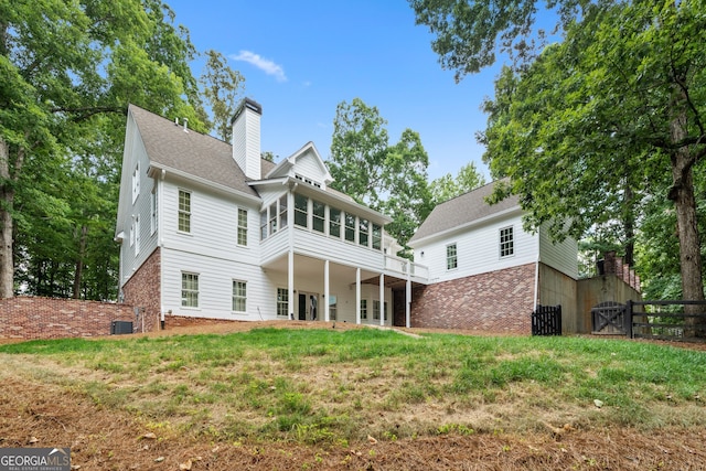 rear view of house featuring a lawn and central AC unit