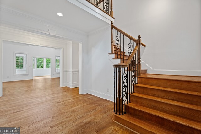 stairway with light hardwood / wood-style flooring and ornamental molding