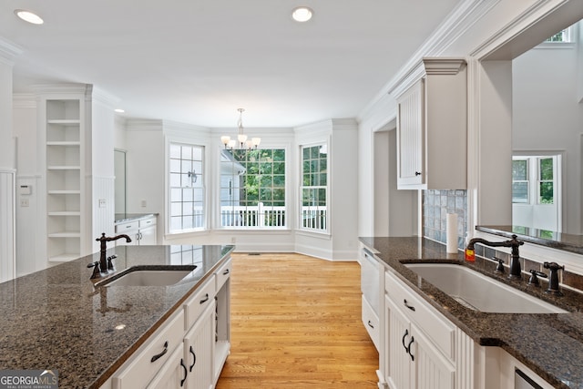 kitchen featuring dark stone counters, a healthy amount of sunlight, light hardwood / wood-style flooring, and sink