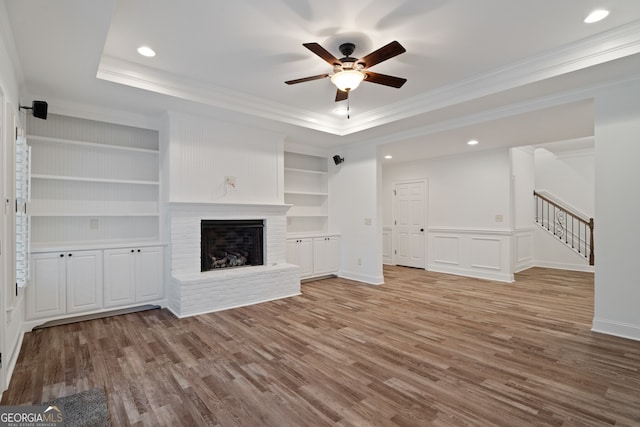 unfurnished living room featuring hardwood / wood-style flooring, a raised ceiling, a fireplace, and ceiling fan