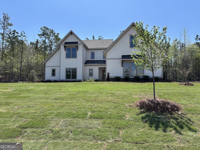 view of front of home featuring a front lawn, roof with shingles, metal roof, and a standing seam roof