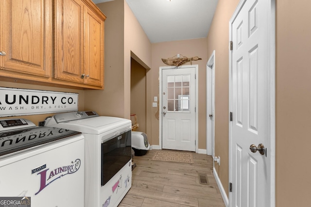 laundry area with independent washer and dryer, cabinets, and light hardwood / wood-style floors