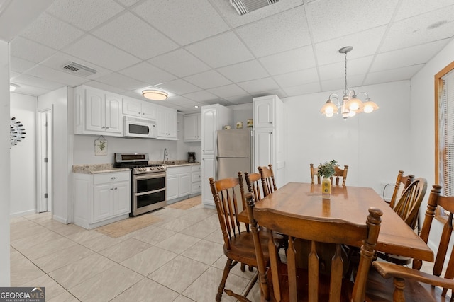 dining room with sink, a paneled ceiling, a notable chandelier, and light tile patterned flooring