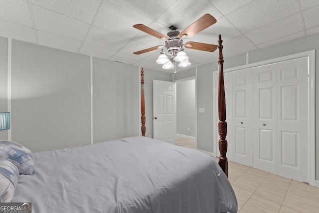 tiled bedroom with a paneled ceiling, a closet, and ceiling fan