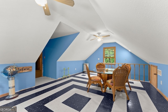 dining area featuring vaulted ceiling, ceiling fan, and a textured ceiling