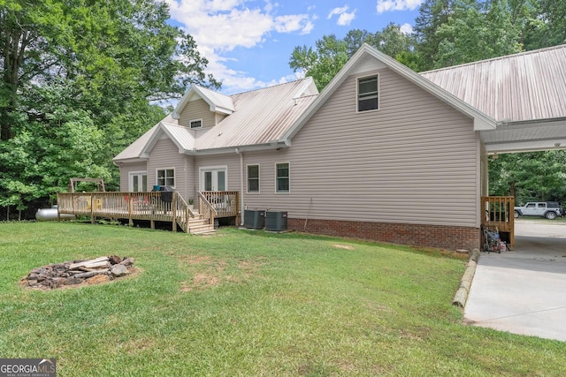 back of property featuring a wooden deck, a fire pit, cooling unit, french doors, and a yard