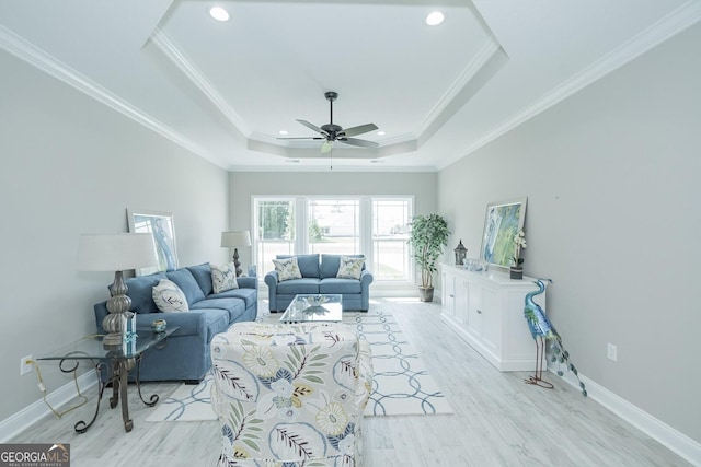 living room with ceiling fan, ornamental molding, light hardwood / wood-style flooring, and a tray ceiling