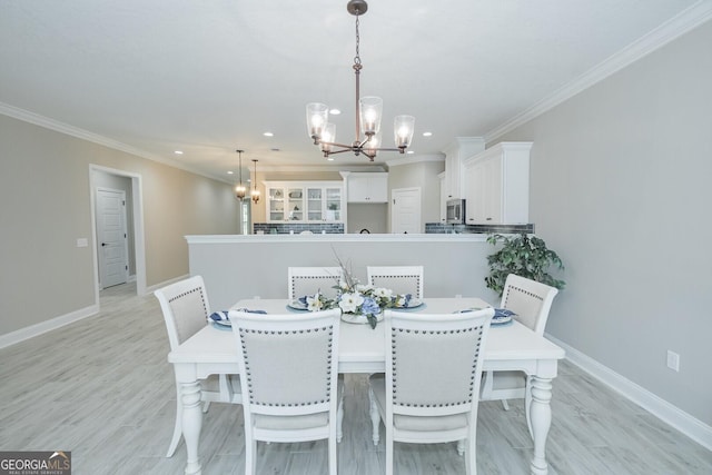 dining room featuring a chandelier, light hardwood / wood-style floors, and crown molding