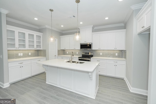 kitchen featuring decorative light fixtures, white cabinetry, stainless steel appliances, an island with sink, and sink