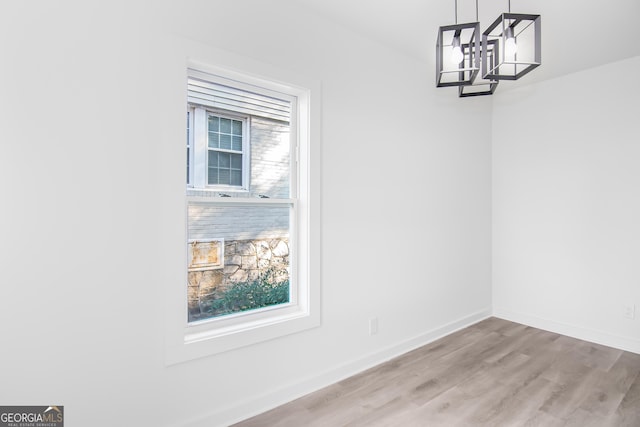 unfurnished dining area with light hardwood / wood-style flooring and an inviting chandelier