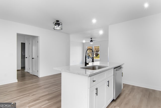 kitchen with white cabinets, sink, light hardwood / wood-style flooring, and an island with sink