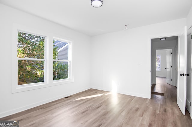 spare room with plenty of natural light and light hardwood / wood-style floors