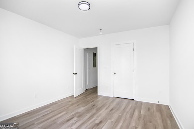 unfurnished bedroom featuring electric panel, light hardwood / wood-style flooring, and a closet