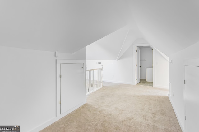 bonus room with lofted ceiling and light carpet