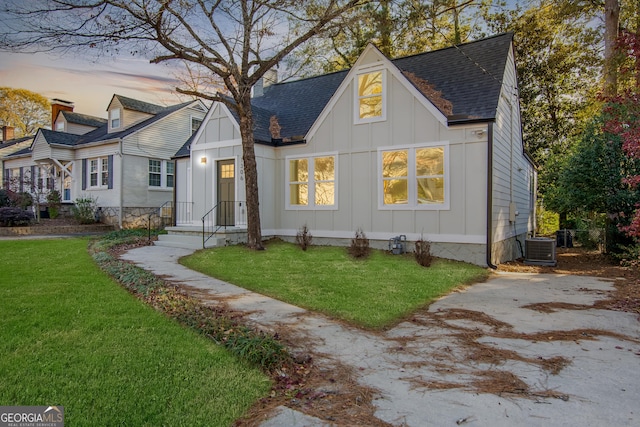 view of front of home featuring a yard and central AC