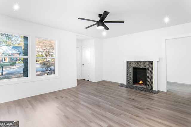 unfurnished living room with hardwood / wood-style flooring, ceiling fan, and a tile fireplace