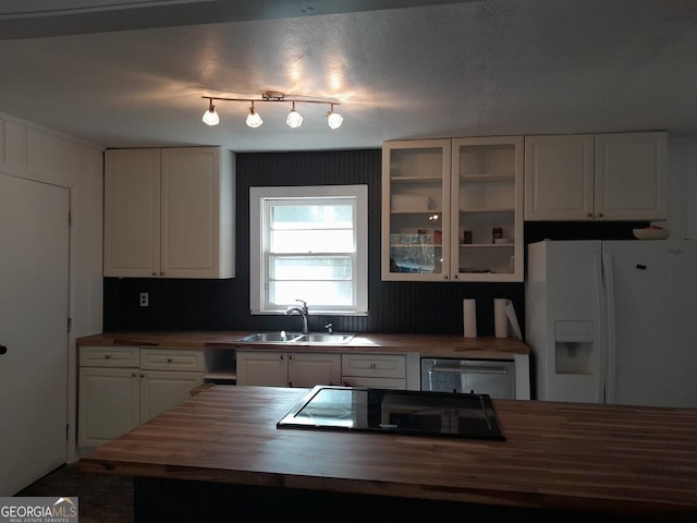 kitchen with wood counters, stainless steel dishwasher, sink, white cabinetry, and white fridge with ice dispenser