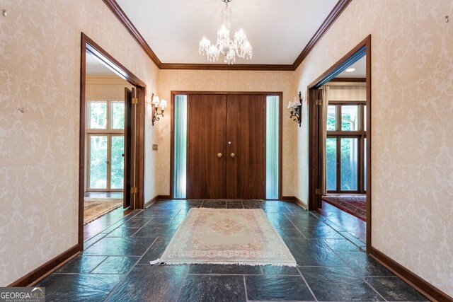 tiled foyer featuring a notable chandelier, a wealth of natural light, and ornamental molding