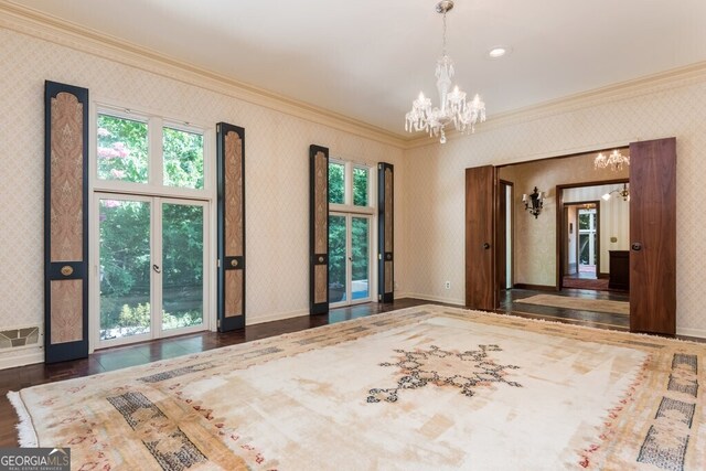 spare room featuring dark hardwood / wood-style floors, a notable chandelier, and crown molding